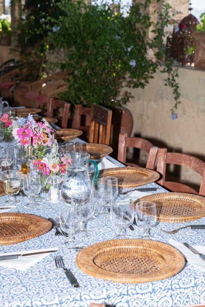 A long table laid for dinner with wine glasses and vases of flowers