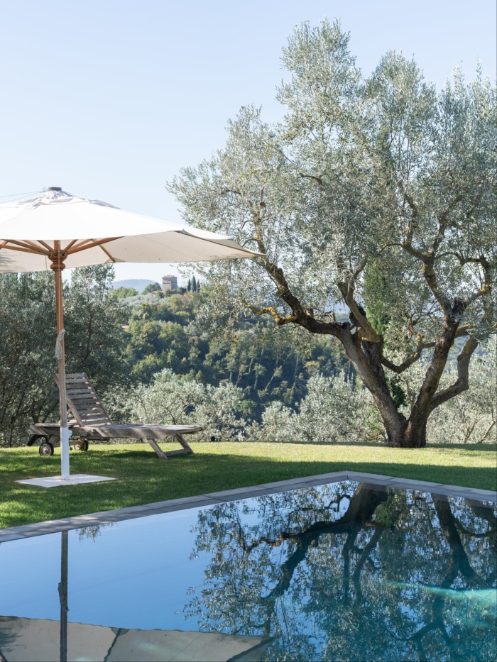 An outdoor swimming pool in the Italian sun with a parasol