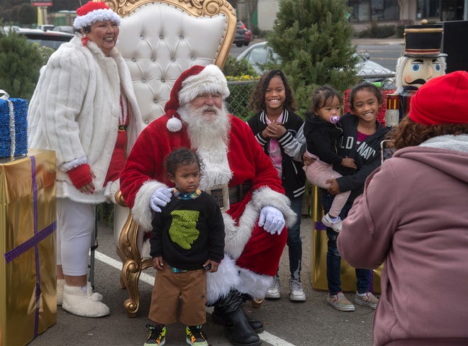 Children pose with Santa and Mrs. Claus at the Mims Corner annual Christmas toy and food giveaway at the Greater Christ Temple church in north Stockton. The is the 11th year for the non-profit's event, and the 2nd year as a drive-thru event due to COVID-19. Organizer Penny Mims says that they prepared 250 boxes of food and bought $3,000-$4000 worth of toys and $6,000 with of bicycles. Home Depot donated $1,000 to the event as well as provided volunteers to help distribute the gifts and food.