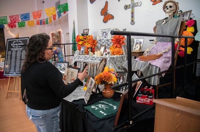 Denise Flores of Stockton takes a picture of an offend or altar on display at the Mexican Heritage Center's 4th annual De Los Muertos Street Fiesta in downtown Stockton on Oct. 28, 2023. The event, at the intersection of Market and Sutter streets, celebrates Mexican culture and remembers past ancestors. Altars, or offends were on display as well as the car show. A Catrina pageant accompanied musical acts as well as food and crafts vendors.