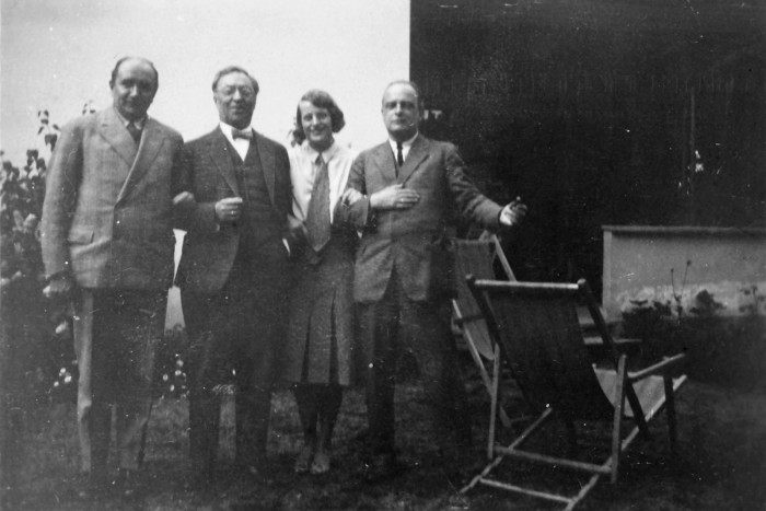 A black and white photograph of Otto Ralfs, Wassily Kandinsky, Käte Ralfs and Paul Klee standing in a row in a garden in Dessau