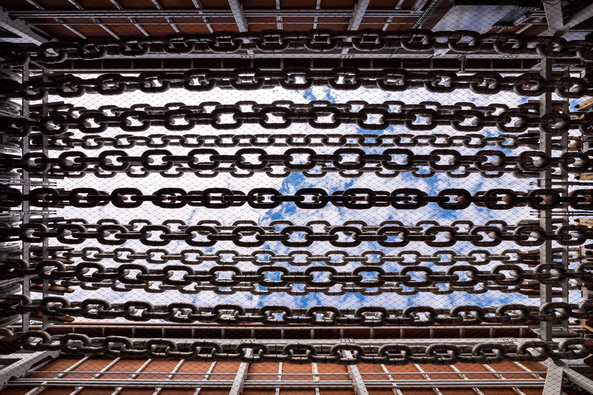 View of nine moving chains against a sunny, cloudy blue sky. 