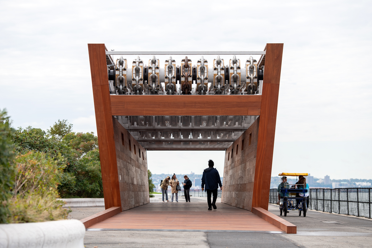 A monumental wooden sculpture that resembles a ship, showing people walking through it. 