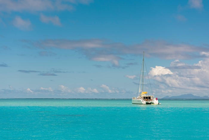 A boat on a turquoise sea, under a blue sky with just a few small white clouds