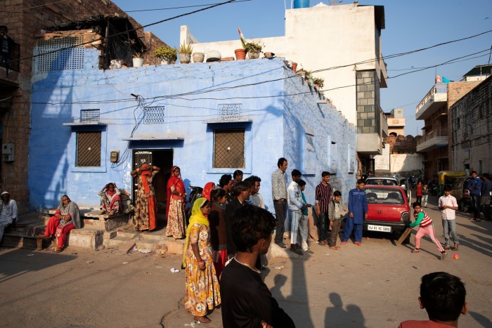 A boy bats away a ball watched by passersby in a busy city street