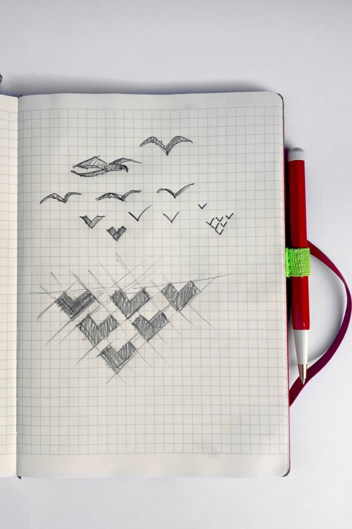 A notebook with pencil sketches of birds in flight and chevrons echoing their shape