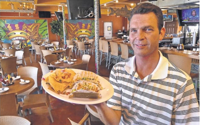 Tom Carmichael holds one of the many dishes served in the renovated Jubilee Oyster Bar and Grille in this 2015 News Journal file photo.