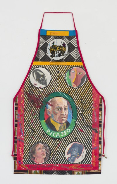 An apron with lined fabrics and an image of a man in circle beneath the word 'PICASSO.' He is surrounded by pictures of masks and Black women.