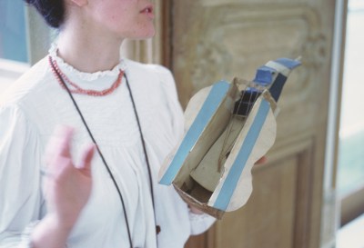 A woman whose head is partially cropped holding a sculpture of an abstracted guitar.