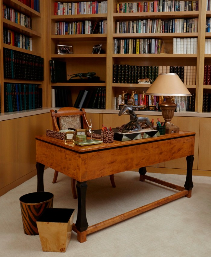 a simple birch desk in a library with lamp, books and wastepaper baskets