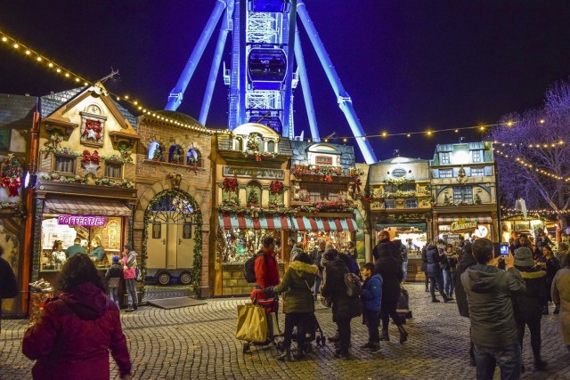 A photograph of a holiday market in Europe at night with small chalets selling a variety of items. 