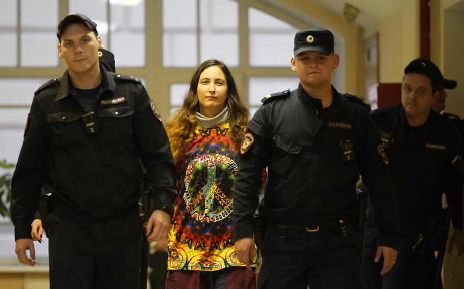 Sasha Skochilenko, a 33 year-old artist and musician, second left, is escorted by officers to the court room for a hearing in the Vasileostrovsky district court in St. Petersburg, Russia, Monday, Nov. 13, 2023. A court in St Petersburg has to deliver a verdict to a young artist Sasha Skochilenko on charges of spreading “fakes” about the Russian military after she replaced four small price tags in a St. Petersburg supermarket with anti-war slogans. The prosecution asked to sentence her to 8 years in prison. 