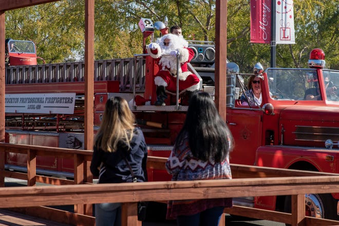 Santa waves from the Stockton Professional Firefighters Local 456 firetruck at the annual Christmas Faire at the Lincoln Shopping Center in Stockton, California, Sunday, Nov, 15, 2020. There are multiple Santa sightings throughout the day. [SARA NEVIS/FOR THE RECORD]