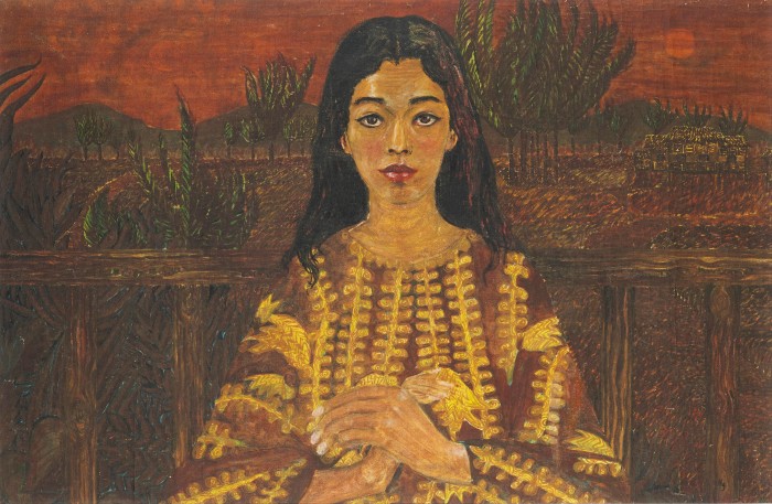A woman with long dark hair and a brown caftan with yellow details looks knowingly at the viewer