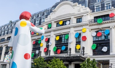 An animatronic Yayoi Kusama with a red bob appears to paint dots on Louis Vuitton's building in France.