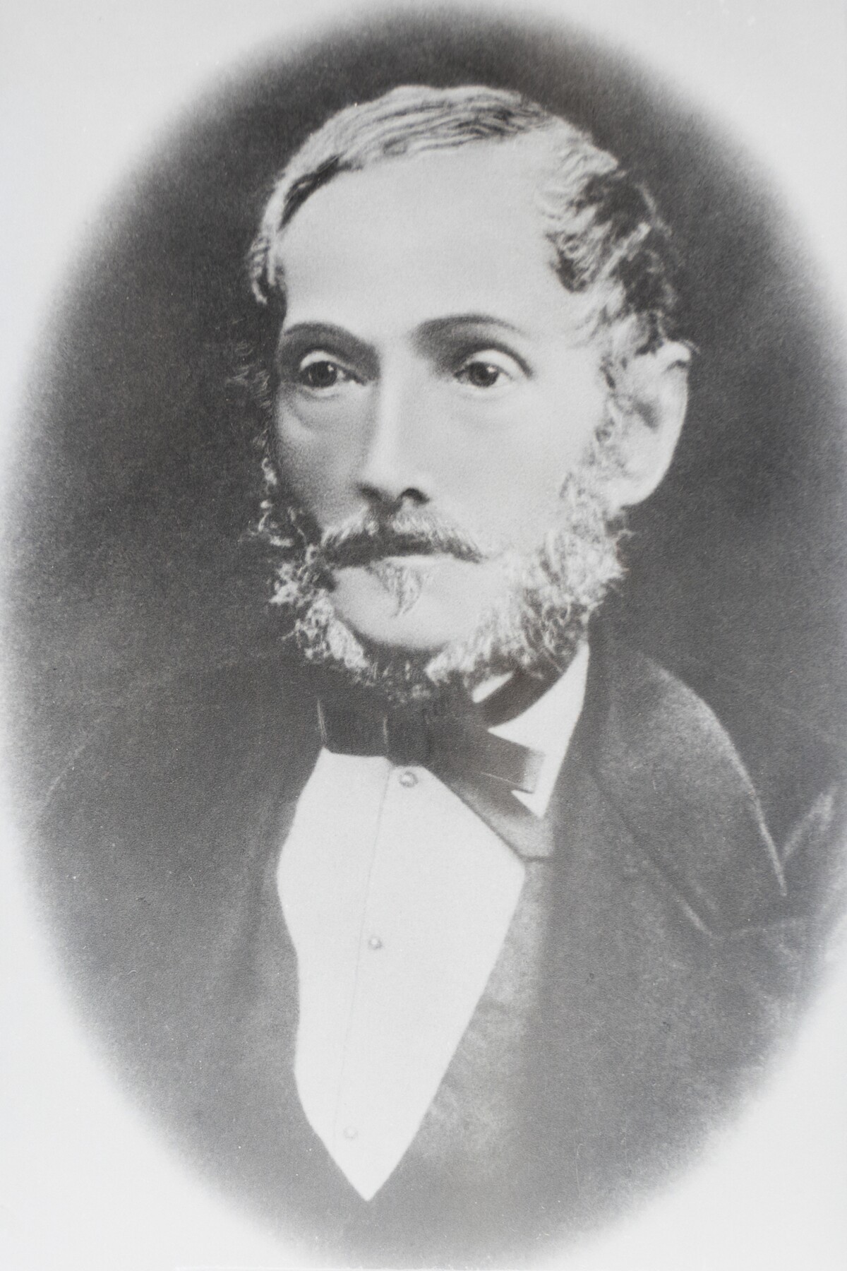 A black and white portrait of a man wearing a suit with a bowtie. 