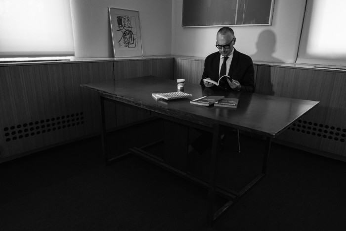 black and white photo of Syracuse architecture dean Michael Speaks at the desk of architect-designer Marcel Breuer