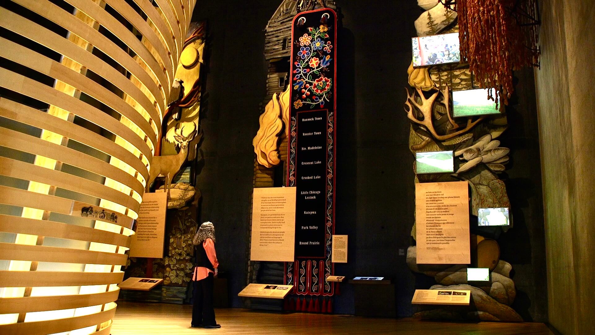 Master beadwork artist Jennine Krauchi standing in a museum viewing a floor-to-ceiling installation of beaded artwork.