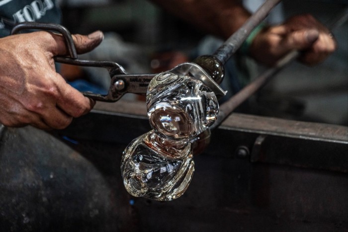 a glassmaker’s hands handling some glass
