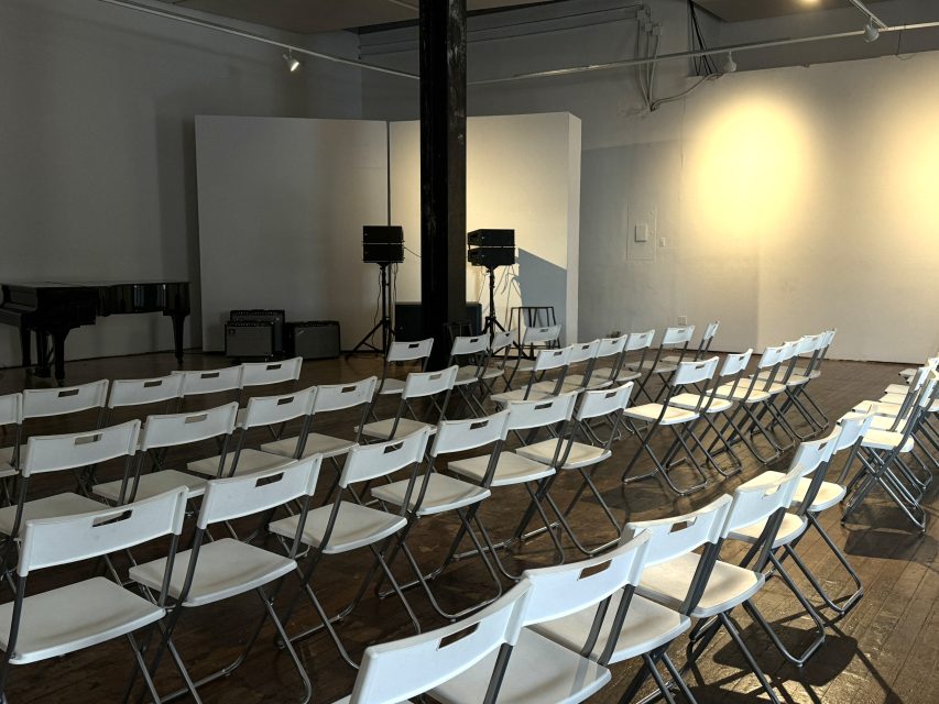 A room with white chairs and a piano.