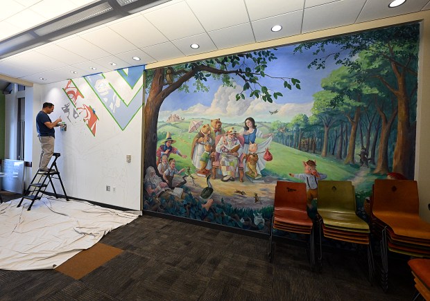 LOVELAND, CO - NOVEMBER 30, 2023: Jeremy Jarvis works on his mural next to another mural Thursday, Nov. 30, 2023, in the children's storytime room at the Loveland Public Library. Youth an help put the finishing touches on the mural Saturday during a painting workshop with Jarvis. (Jenny Sparks/Loveland Reporter-Herald)