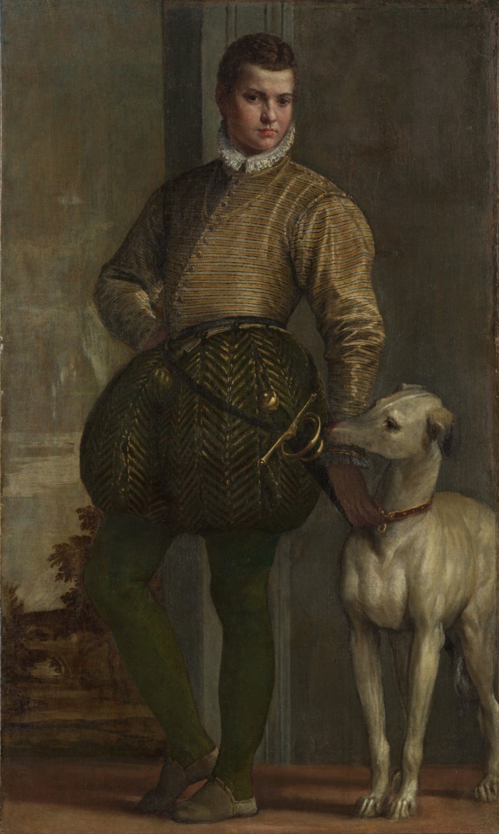 A boy dressed in fine green and gold costume with a greyhound dog