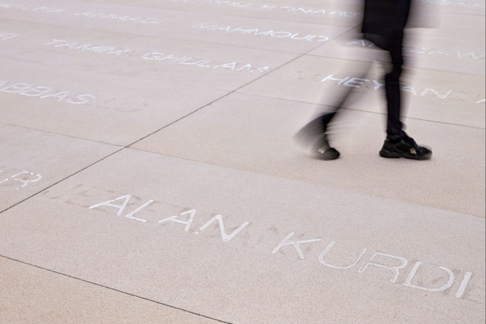 A figure walks over a pavement inscribed with names 