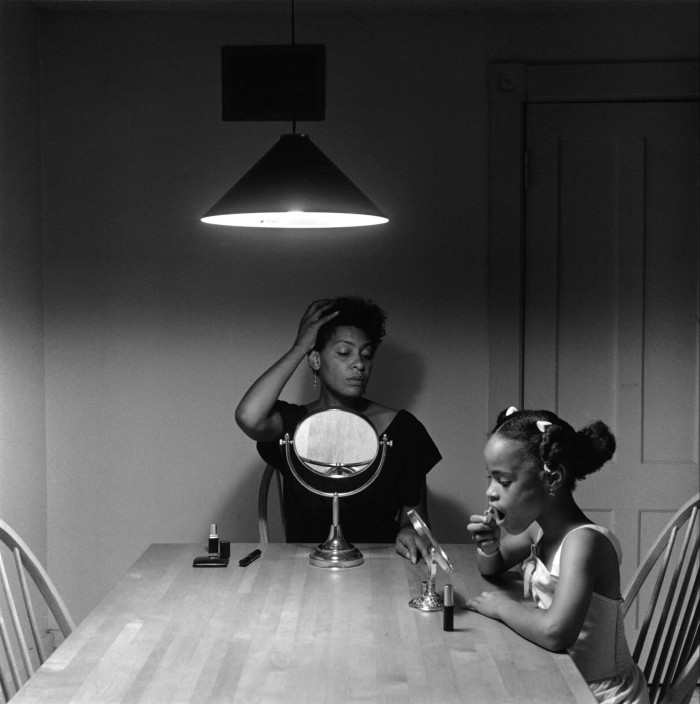 A woman and a young girl sit in front of small mirrors at a table