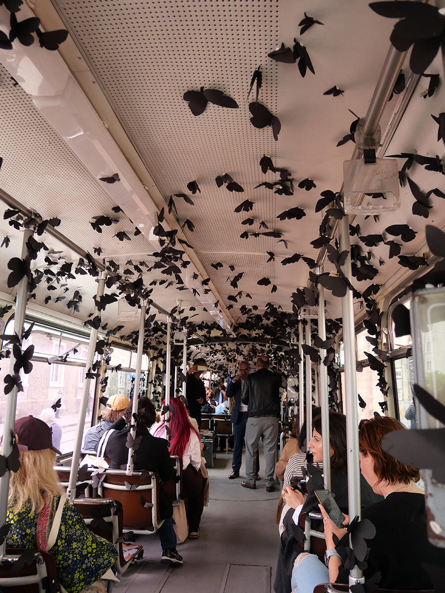 A tram covered in black paper butterflies.