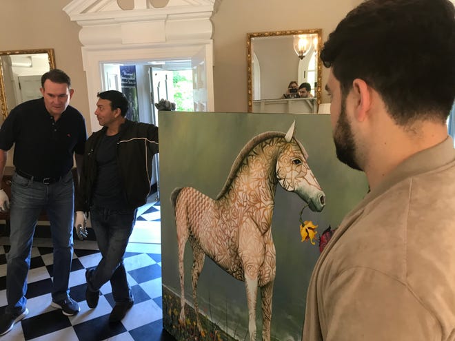 Left to Right: SAMFA board member Jeff Curry, San Angelo artist René Alvarado, and volunteer Taylor Velarde pause while carrying a painting into the European Union residence on May 15, 2019. The art is on loan from the San Angelo Museum of Fine arts until May 2020.