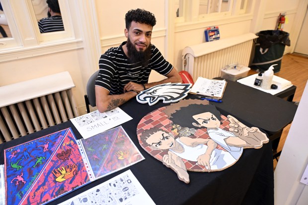 Tattoo artist Jeremy Reed with examples of his art at the Arts Market sponsored by Barrio Alegria on Saturday at the WCR Center for the Arts, 140 N. Fifth St. (BILL UHRICH - READING EAGLE)