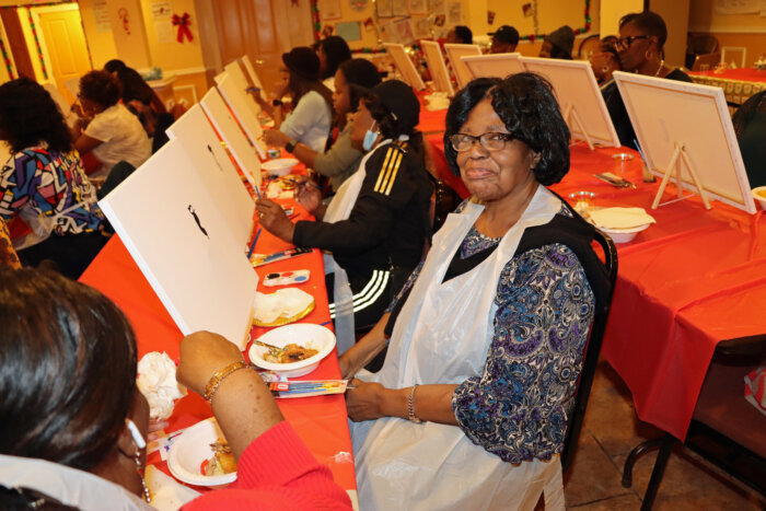 Barbara Castleberry, in foreground, work on her art while snacking.