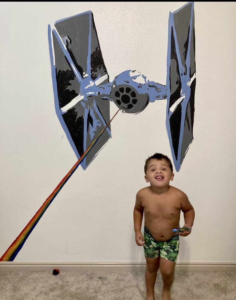 Kimberly Ipson's son stands next to a painting on his bedroom in St. George, Utah, date unspecified | Photo courtesy of Kimberly Ipson, St. George News