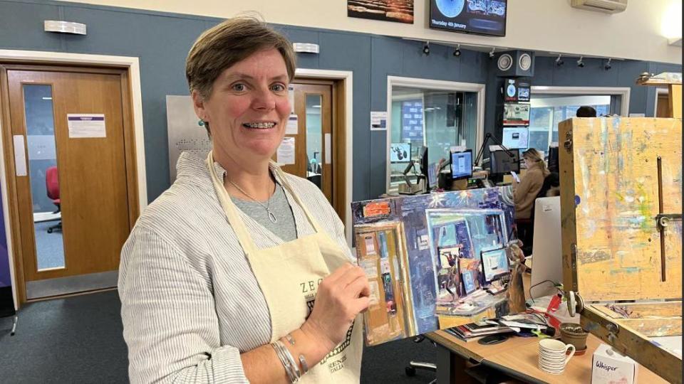 Rosanne Guille holding painting in front of radio studio