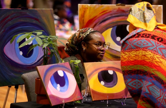 Artist Solar Michelle talks with a patron while surrounded by art during the 2nd annual Savannah Black Art Expo on Saturday, February 3, 2024 at the Savannah Cultural Arts Center.