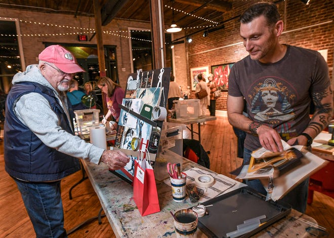 Jim Davidson, left, of Anderson votes for Chris Stanzione who finished "Climbing the Corporate Ladder" mixed-media piece during the 2024 Art Slam! at Anderson Arts Center Friday, February 9, 2024.
