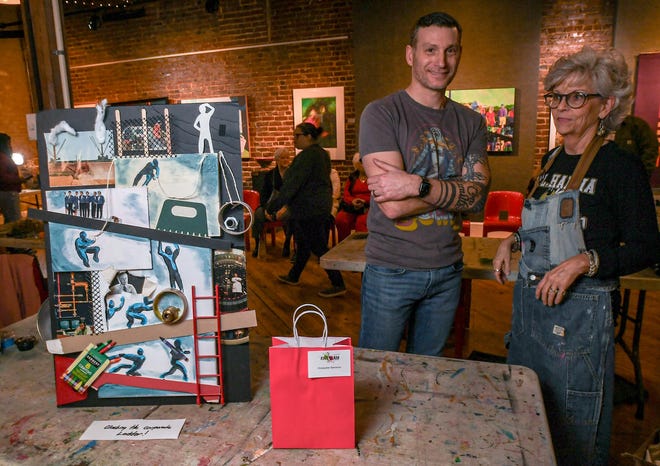 Chris Stanzione, left, near his finished mixed-media art competition piece "Climbing the Corporate Ladder" near Kathy Moore during the 2024 Art Slam! at Anderson Arts Center Friday, February 9, 2024.