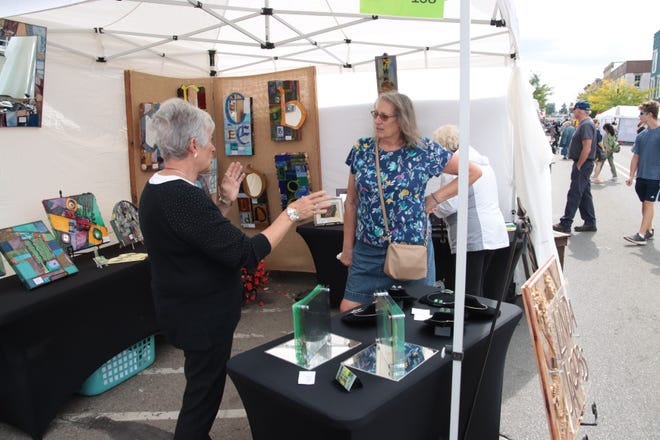 Glass artist Linda Jacobs of Adrian talks with Cindy Frownfelder of Adrian Sunday, Sept. 23, 2023, during Artalicious in downtown Adrian.