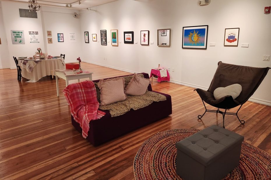 An art gallery with prints displayed on a couch and chairs.