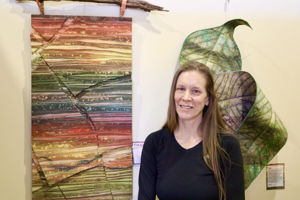 Textile Artist Teri McHale stands next to her layered wall art at the Arrowhead Gallery in St. George, Utah, Feb. 22, 2024 | Photo by Jessi Bang, St. George News