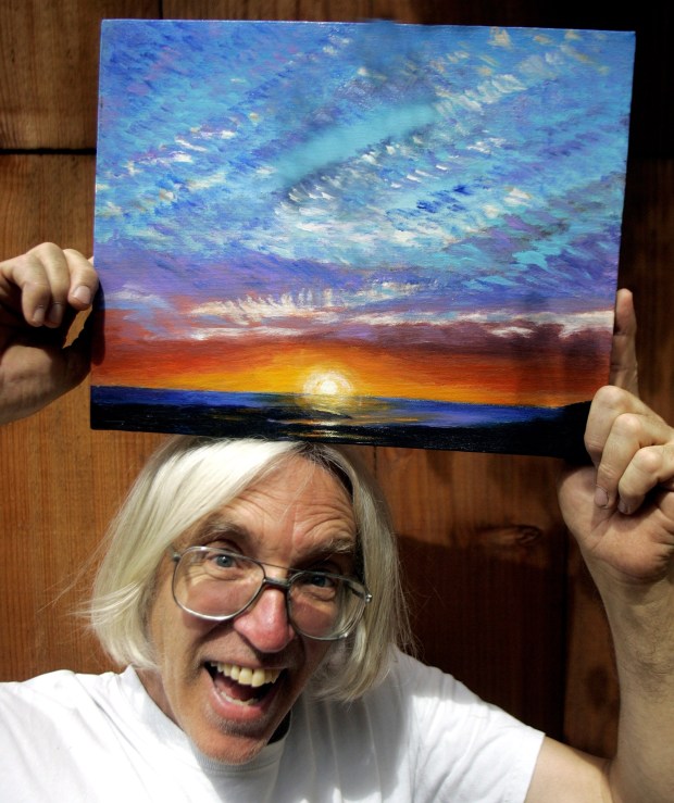 Laguna Beach artist Douglas Miller with a painting of Wood's Cove at sunset in this file photo. He is a longtime Sawdust Festival artist. (Photo by Mindy Schauer, The Orange County Register)