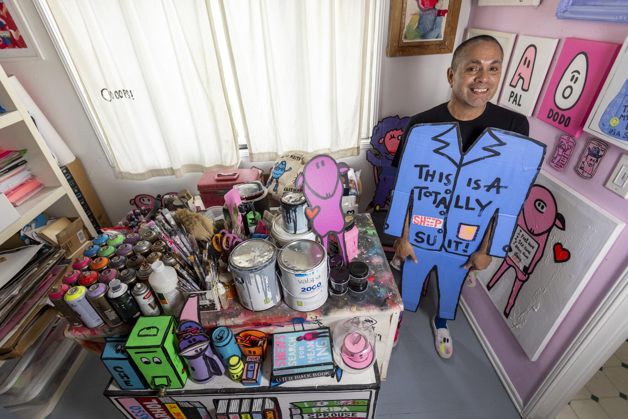 An artist surrounded by art supplies while carrying street art creations. 