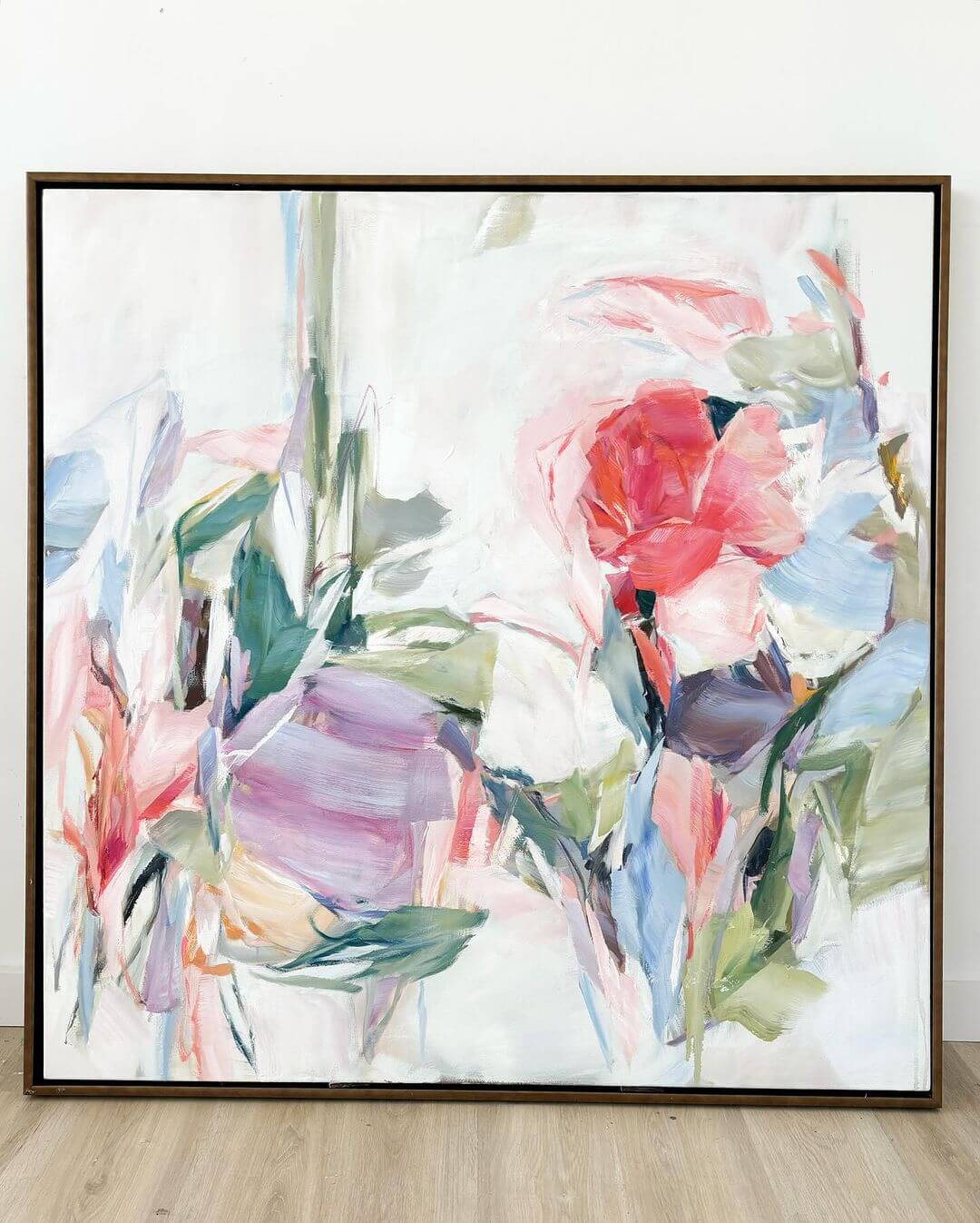 Abstract floral painting by Liz Lane in a wooden frame against a plain wall.