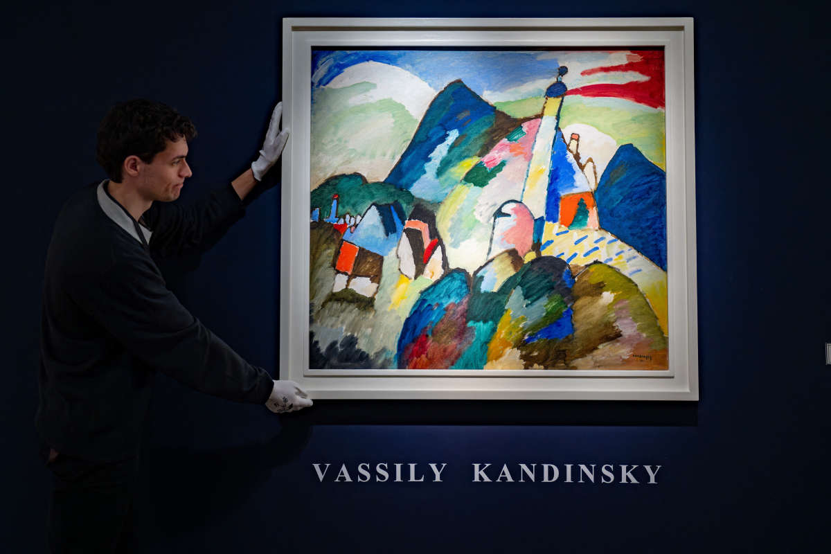 A personnel member hangs for display a Wassily Kandinsky painting, &lsquo;Blick auf Murnau mit Kirche II&rsquo;, (View of Murnau with Church 2). Photo: Nick Gammon/AFP