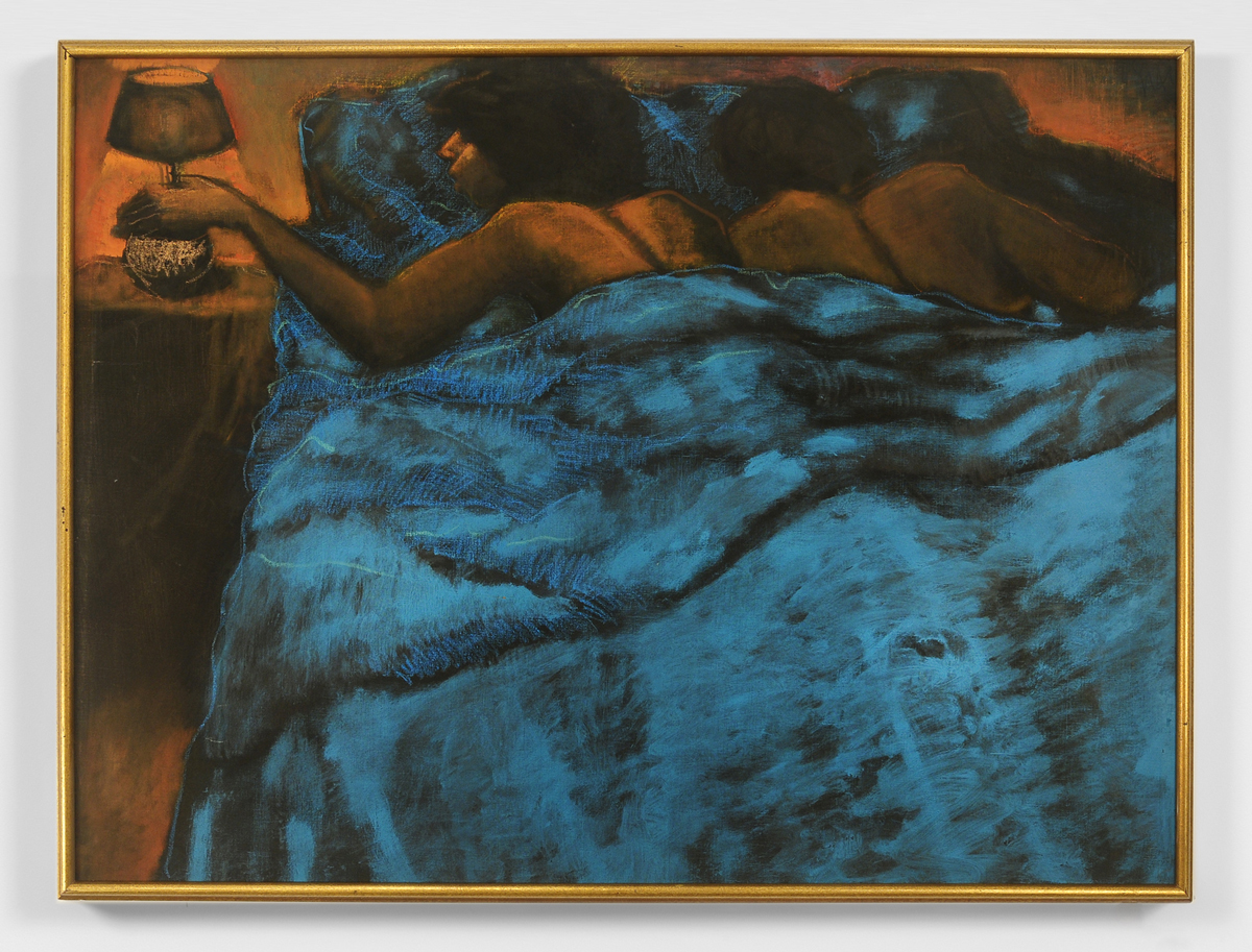 A Black couple lies in bed with a brilliant blue comforter. The woman reaches over to turn off the bedside lamp. 