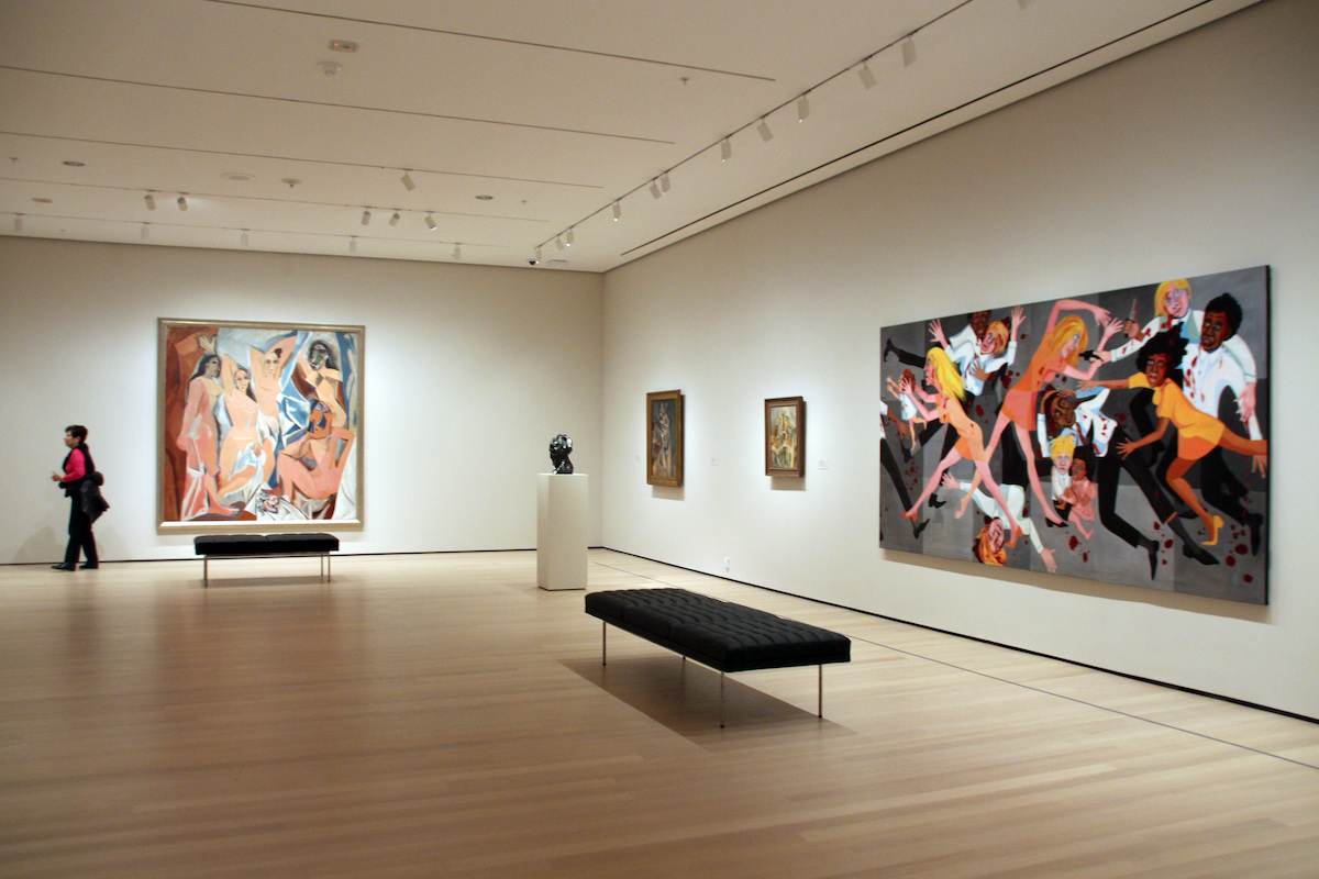 A gallery that foregrounds two paintings, one showing a group of white woman posed together in various states of disrobe, the other showing a crush of white and Black figures doing violence to one another.