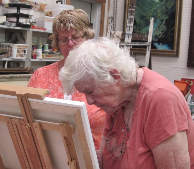 Adele Pruitt, an original member of MCAA, demonstrating an oil painting technique to Student, Bev Rae.