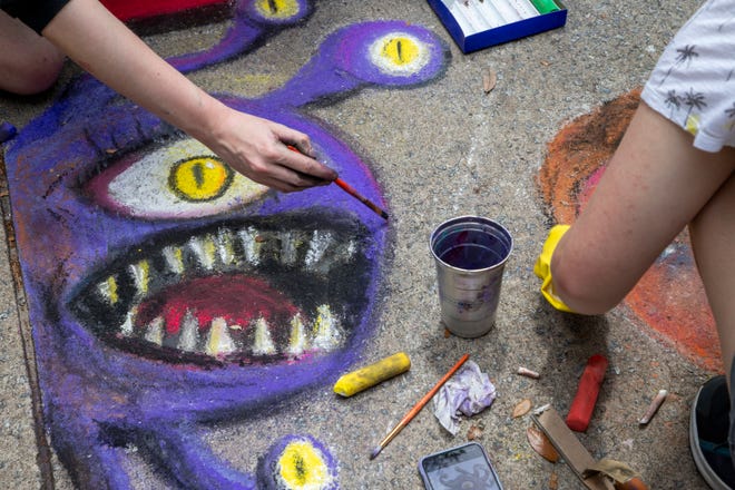 Students draw a purple monster at the SCAD Sidewalk Arts Festival, on April 27, 2024, in Savannah, GA.