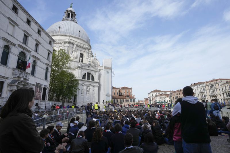 Pope Francis, background center, delivers his message in front of the Church of the Salute during his meeting with youths in Venice, Italy, Sunday, April 28, 2024. The Pontiff arrived for his first-ever visit to the lagoon town including the Vatican pavilion at the 60th Biennal of Arts. (AP Photo/Alessandra Tarantino)