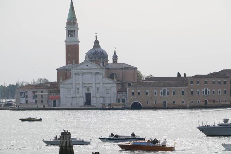 Pope Francis, aboard a motorboat foreground, passes past the Church of San Giorgio Maggiore upon his arrival in Venice, Italy, Sunday, April 28, 2024. The Pontiff arrived for his first-ever visit to the lagoon town including the Vatican pavilion at the 60th Biennal of Arts. (AP Photo/Alessandra Tarantino)